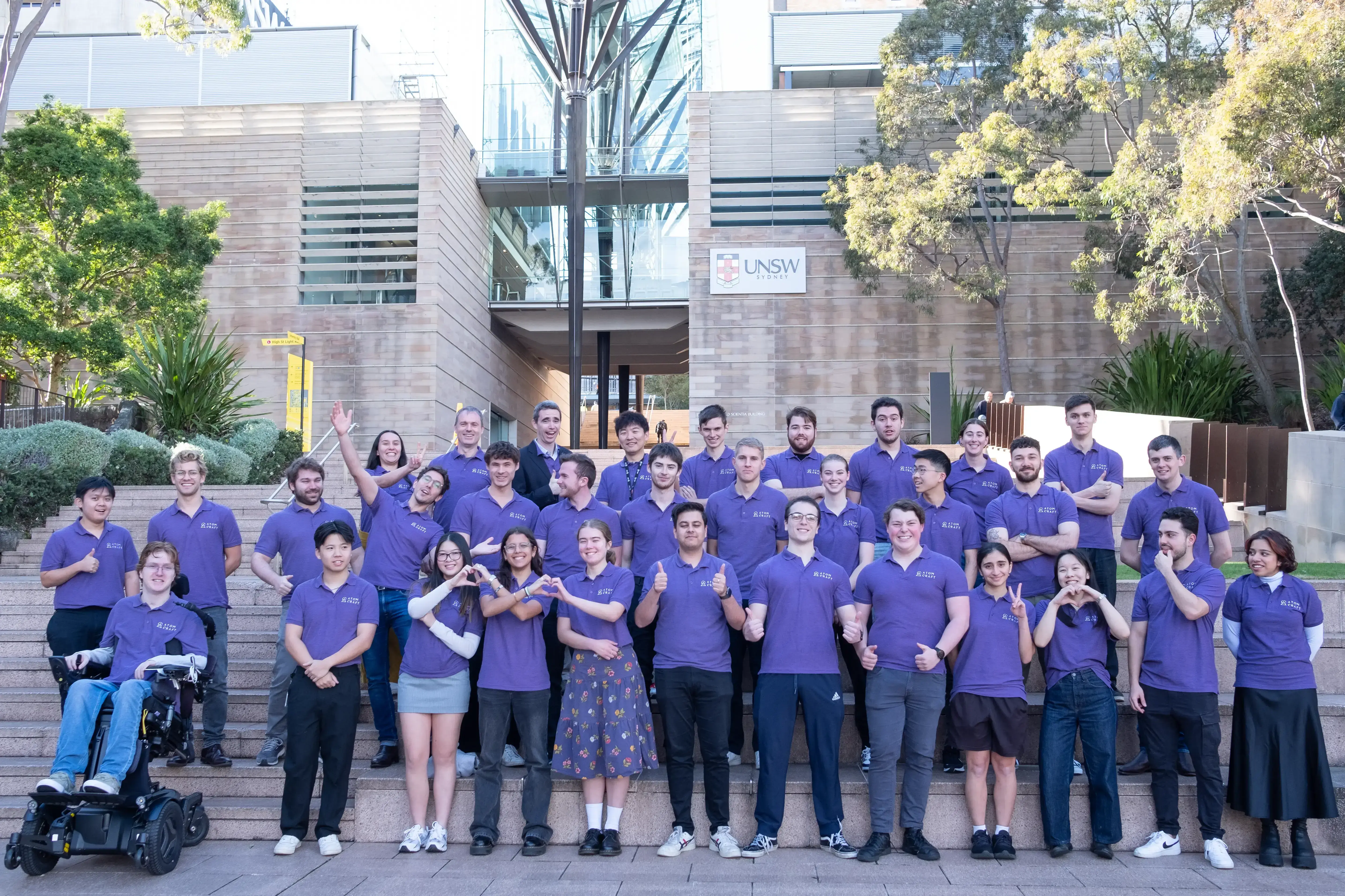 Rows of AtomCraft team members lined up making gestures